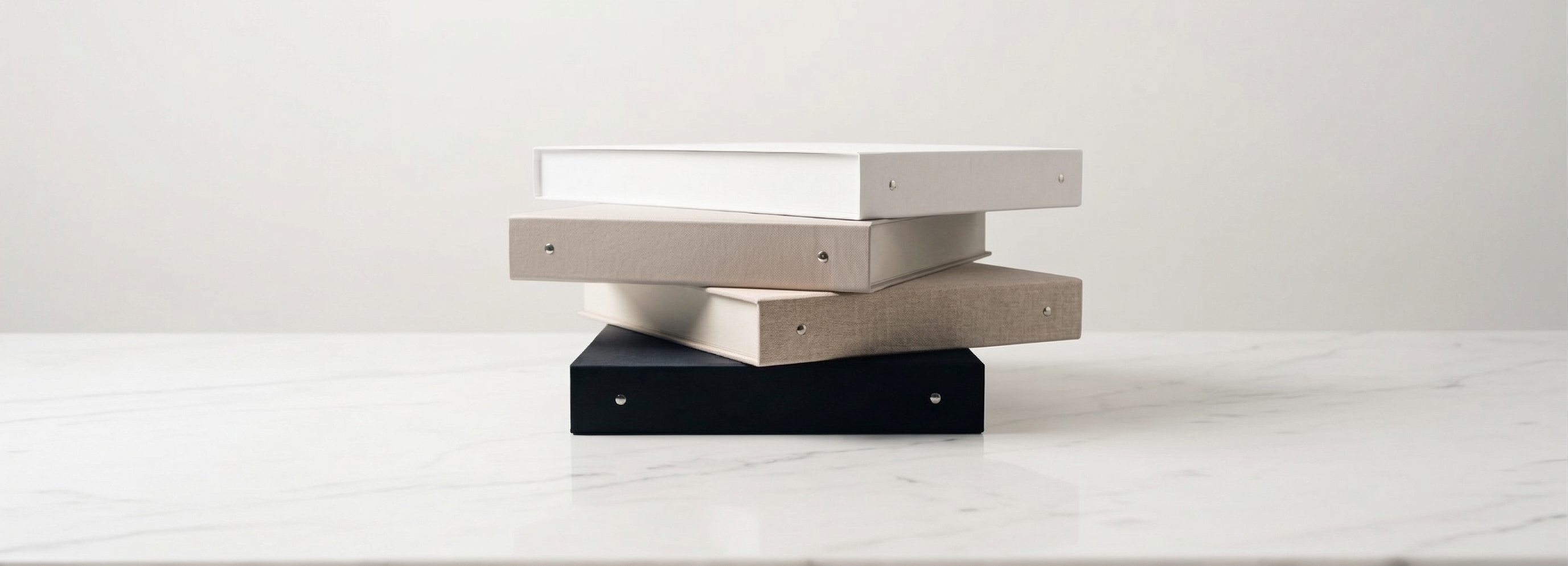 Estuches premium Atelier Brands apilados sobre superficie clara